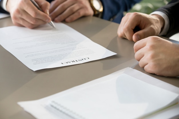 Businessman signing contract at meeting, focus on document, clos