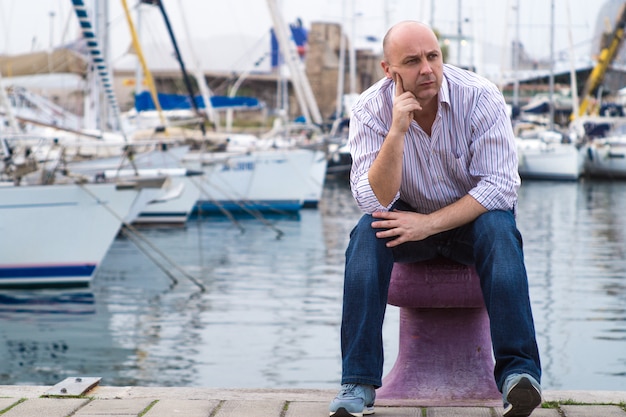 Бизнесмен сидит на дорогих парусных лодок и яхт в прибрежном городе