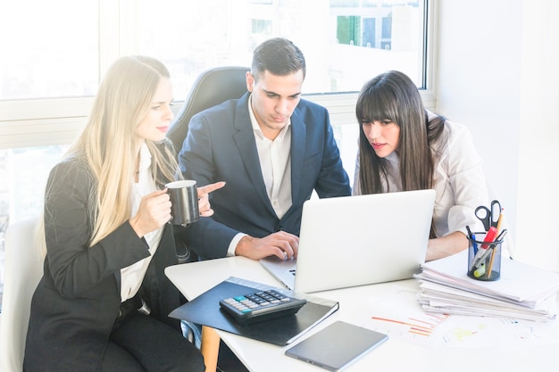 Businessman sitting with two women working in the office