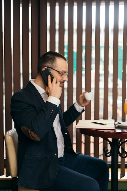 Businessman speaking on phone and drinking coffee