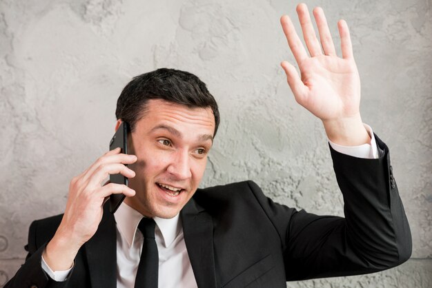 Бизнесмен говорит по телефону и машет рукой