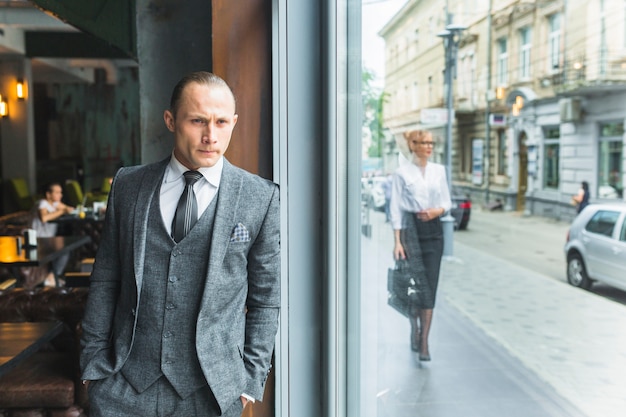 Foto gratuita finestra del caffè in piedi uomo d'affari