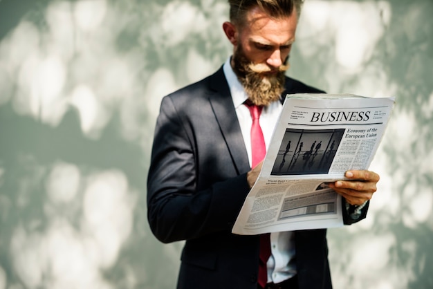 Free photo businessman standing and reading newspaper