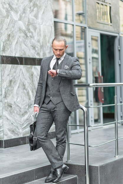 Businessman standing on staircase checking time on wristwatch