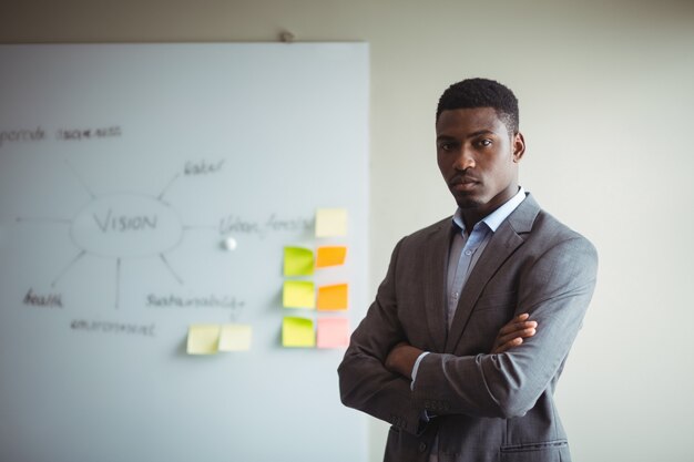 Businessman standing with arms crossed in office