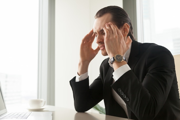 Бизнесмен страдает от мигрени или головной боли
