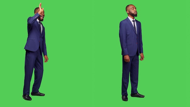 Free photo businessman in suit greeting people and waving, saying hello or goodbye in studio over greenscreen. male startup employee feeling confident on camera posing, full body backdrop.