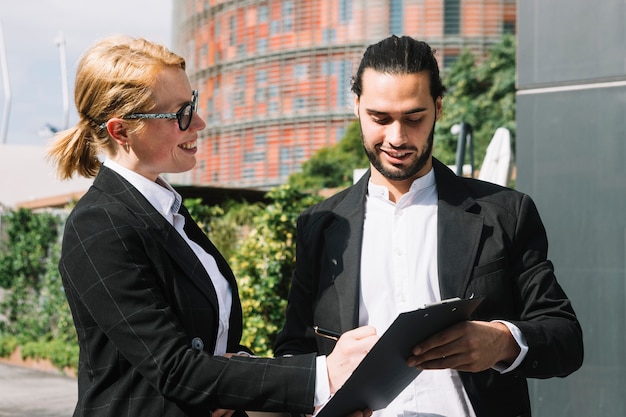Businessman taking signature on document from businesswoman at outdoors