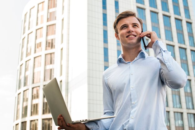 Businessman talking on the phone holding laptop