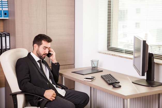 Бизнесмен разговаривает по телефону и работает в офисе. Деловой человек в профессиональной среде