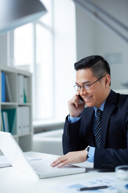 Businessman talking and typing on laptop