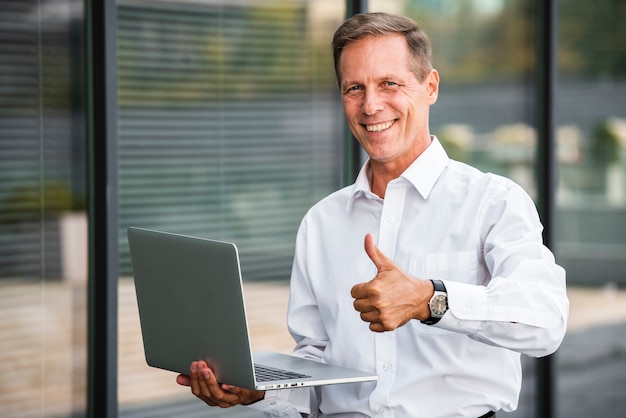 Businessman thumbs up holding laptop