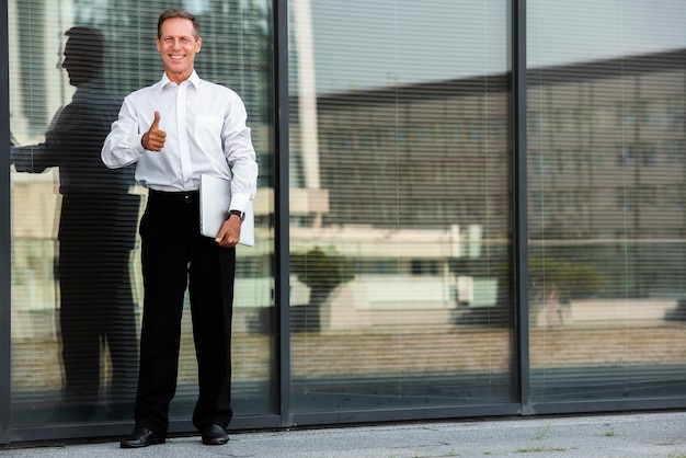 Free photo businessman thumbs up near building