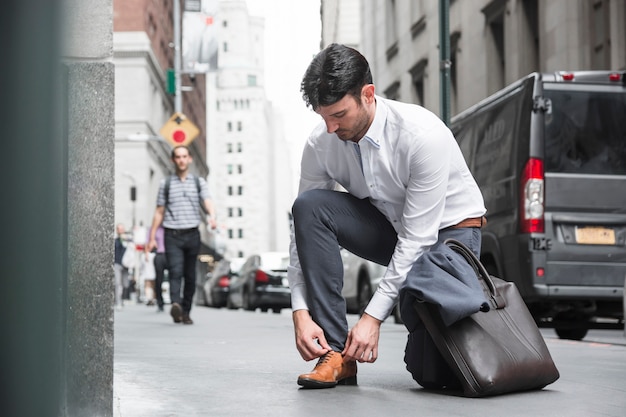 Free photo businessman tying laces near road