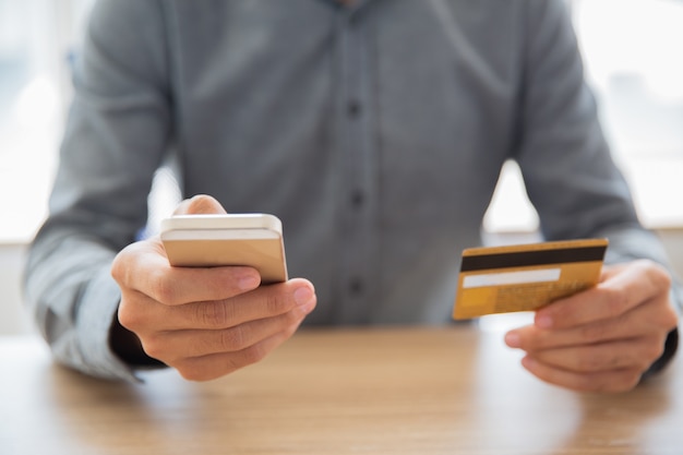 Businessman typing card data on mobile phone