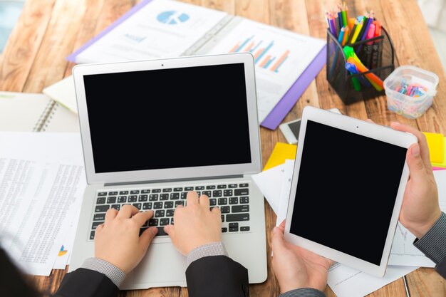 Businessman typing on a laptop and with a tablet next