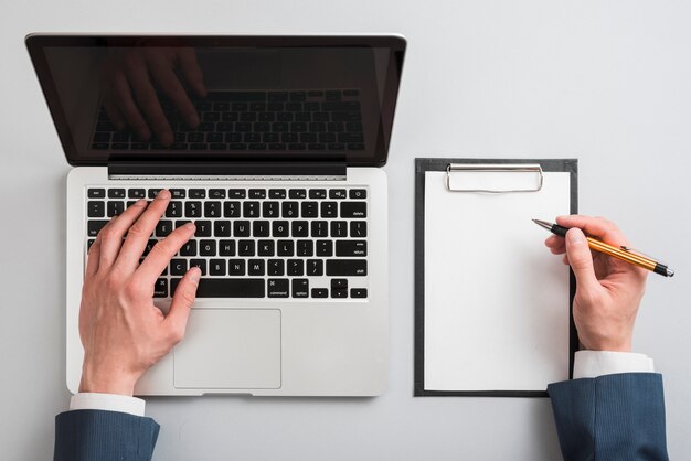 Businessman using laptop and clipboard