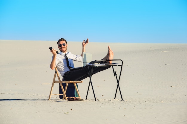 Businessman using laptop in a desert