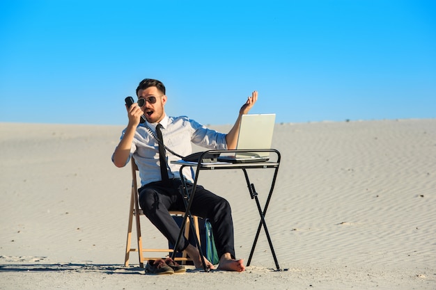 Businessman using  laptop in a desert