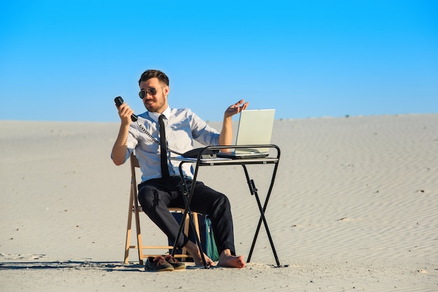 Businessman using laptop in a desert