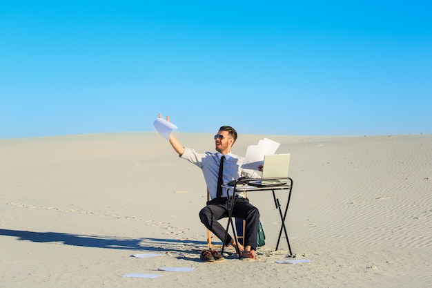 Businessman using laptop in a desert