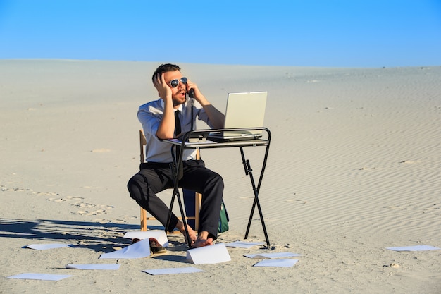 Businessman using laptop in a desert