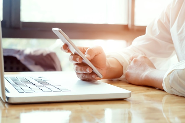 Businessman using laptop and mobile phone.