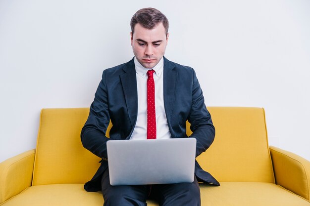 Businessman using laptop on sofa