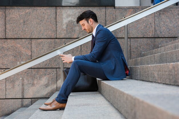 Businessman using smartphone on steps