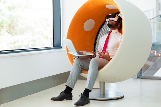 Businessman using virtual reality simulator for meditating