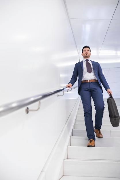 Free photo businessman walking down steps