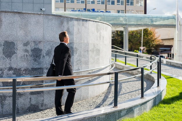 Free photo businessman walking near railing at outdoors