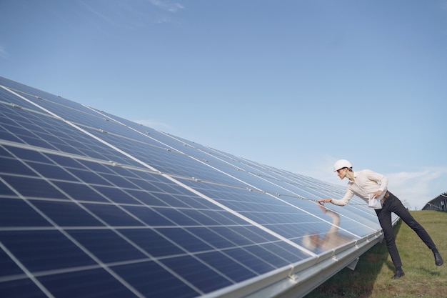 Бизнесмен в белом шлеме возле солнечной батареи