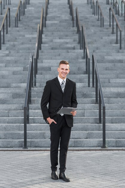 Free photo businessman with clipboard in front of stairs