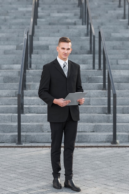 Free photo businessman with clipboard in front of stairs