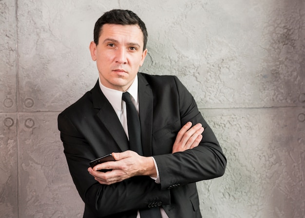 Free photo businessman with crossed arms leaning on wall