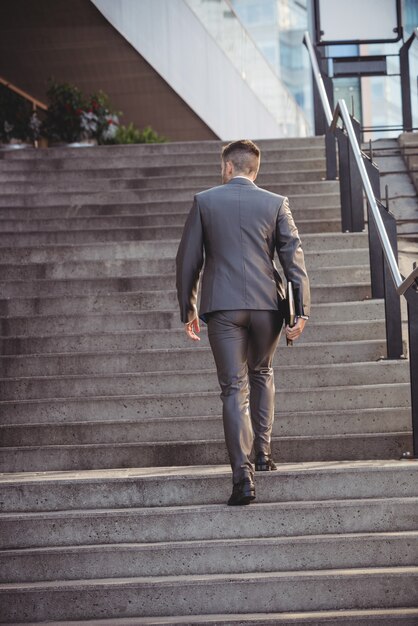 Businessman with a diary climbs up stairs