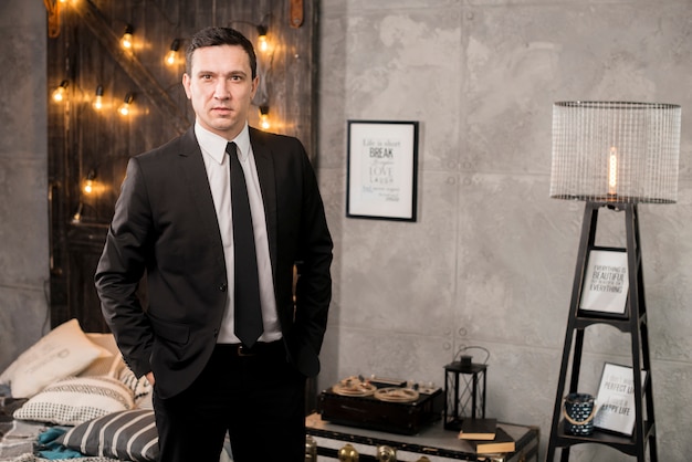 Businessman with hands in pockets standing in bedroom 