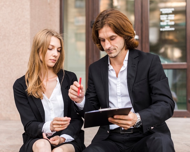 Businessman with his colleague signing on a clipboard