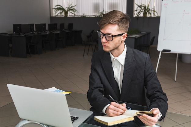 Businessman with his diary looking at laptop