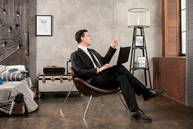 Free photo businessman with laptop pointing away and pondering