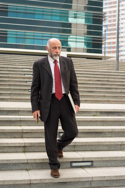 Businessman with laptop and smartphone walking on steps