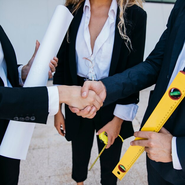 Businessman with level and businesswoman shaking hands
