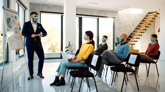 Businessman with protective face mask giving a presentation during a seminar in board room