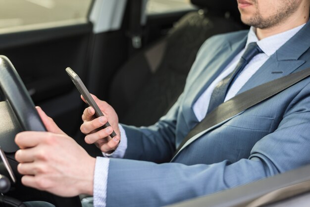 Businessman with smartphone in car