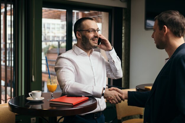 Businessman with smartphone greeting man