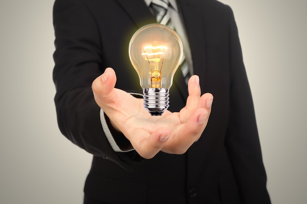 Businessman with stiffened hand and a lit light bulb