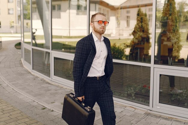 Businessman with suitcase walking in a summer city