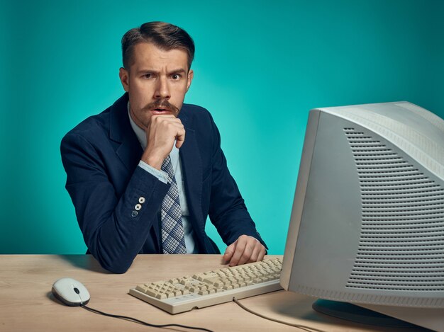 Businessman with suspicious look sitting at desk in front of computer