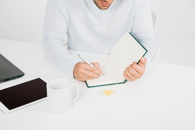 Businessman with tablet writing on his diary